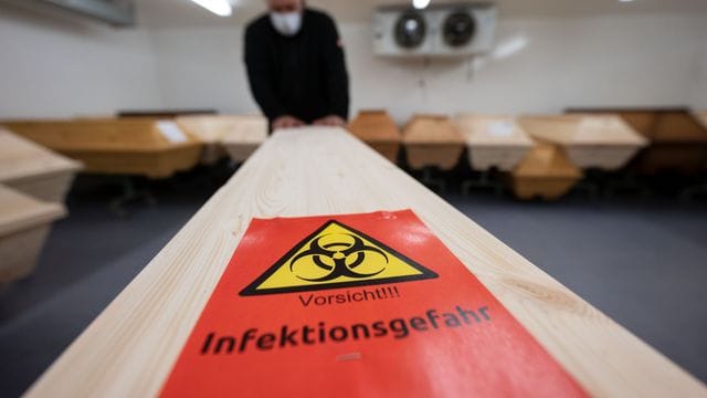 Ein Mitarbeiter eines Krematoriums mit einem Sarg eines Menschen, der mit Covid-19 verstorben ist. Ein Mitarbeiter eines Krematoriums mit einem Sarg eines Menschen, der mit Covid-19 verstorben ist.