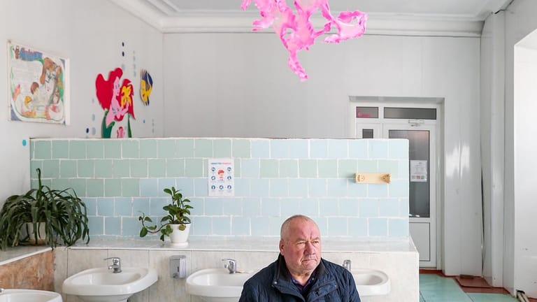 Kutscha in der Ukraine: Wladimir Getmantschuk, Direktor einer Sonderschule, sitzt in einem Waschraum unter einer Installation des Künstlers Aljoscha.
