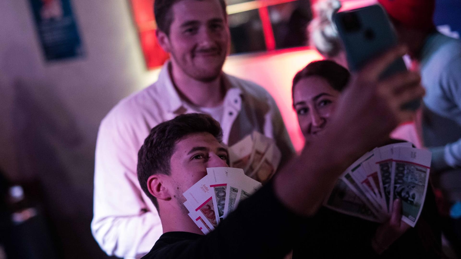 Drei Gäste posieren mit Händen voller Muccarones für ein Selfie: Veranstaltet wird das Kneipen-Event von einer großen Brauerei.