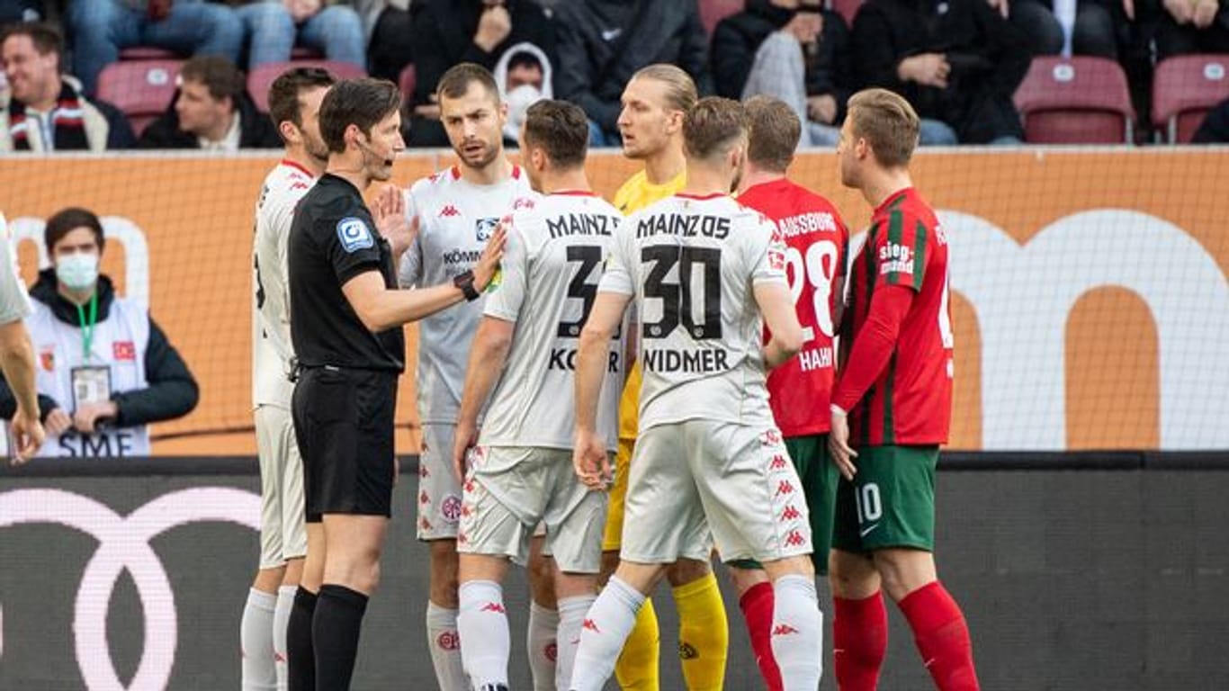 Die Mainzer Spieler diskutieren mit Schiedsrichter Matthias Jöllenbeck (l).