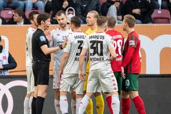 Die Mainzer Spieler diskutieren mit Schiedsrichter Matthias Jöllenbeck (l).