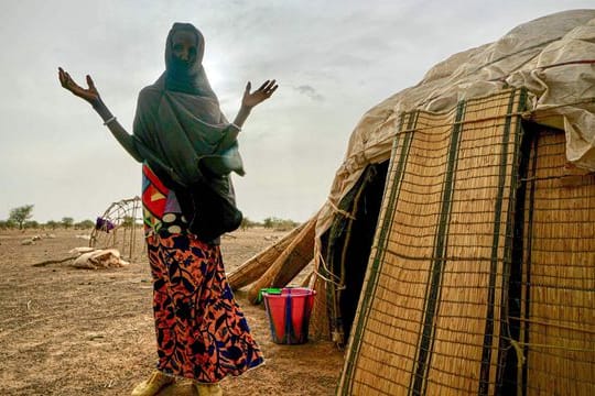 Eine Frau steht neben ihrer Hütte in einer von den Vereinten Nationen unterstützten Siedlung für Binnenflüchtlinge in Burkina Faso.