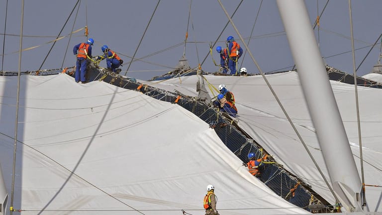 Dutzende Arbeiter, an Seilen gesichert, befestigen die Dachkonstruktion (Archivbild): Einige Firmen werden der Ausbeutung bezichtigt.