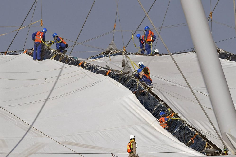 Dutzende Arbeiter, an Seilen gesichert, befestigen die Dachkonstruktion (Archivbild): Einige Firmen werden der Ausbeutung bezichtigt.