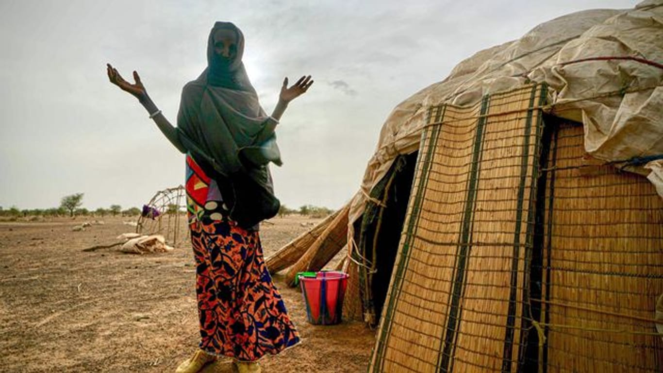 Eine Frau steht neben ihrer Hütte in einer von den Vereinten Nationen unterstützten Siedlung für Binnenflüchtlinge in Burkina Faso.