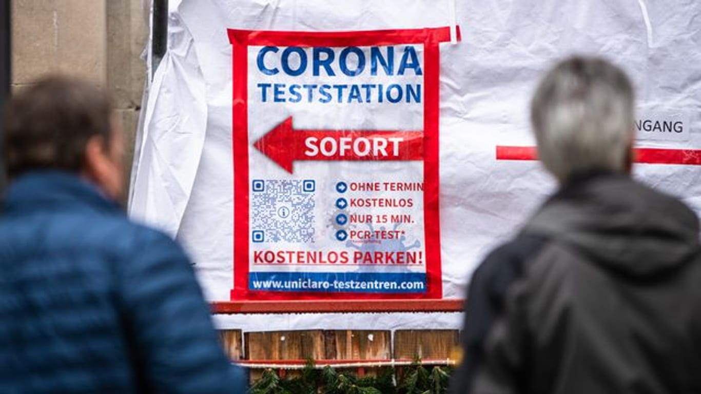 Menschen warten in der Stuttgarter Innenstadt vor einem Corona-Testzentrum auf ihren Abstrich.