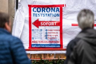 Menschen warten in der Stuttgarter Innenstadt vor einem Corona-Testzentrum auf ihren Abstrich.