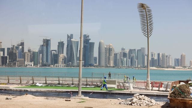 Arbeiter sind auf einer Baustelle an der Promenade Corniche mit Blick auf die Skyline von West Bay Doha zu sehen.