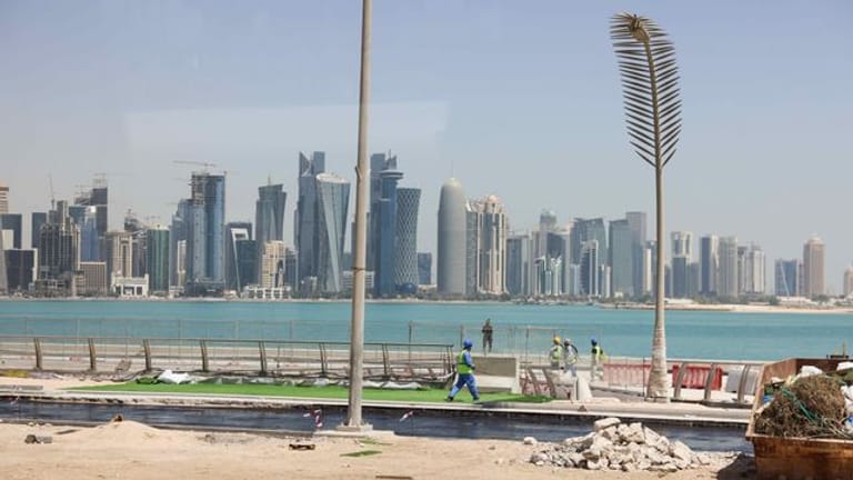 Arbeiter sind auf einer Baustelle an der Promenade Corniche mit Blick auf die Skyline von West Bay Doha zu sehen.