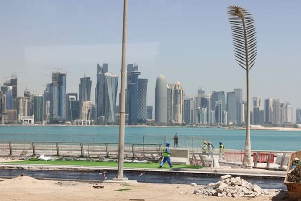 Arbeiter sind auf einer Baustelle an der Promenade Corniche mit Blick auf die Skyline von West Bay Doha zu sehen.