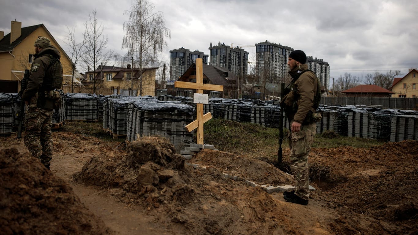Ein ukrainischer Soldat steht neben einem Grab in Butscha: Laut dem BND planten russische Truppen offenbar den Mord an den Zivilisten per Funkspruch.