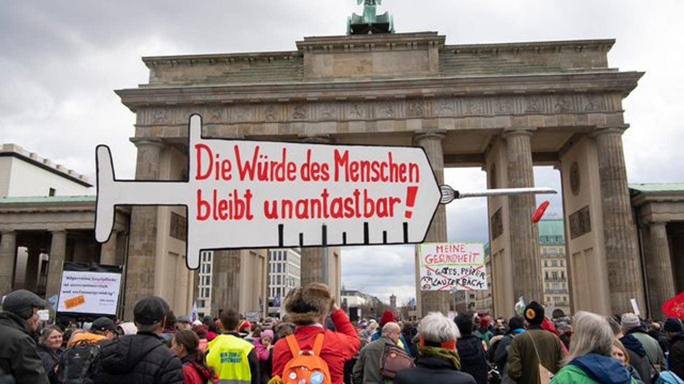Impfpflicht-Gegner stehen bei einer Kundgebung vor dem Brandenburger Tor in Berlin, während der Bundestag über die Einführung einer Impfpflicht debattiert.