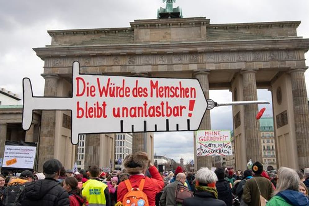 Impfpflicht-Gegner stehen bei einer Kundgebung vor dem Brandenburger Tor in Berlin, während der Bundestag über die Einführung einer Impfpflicht debattiert.