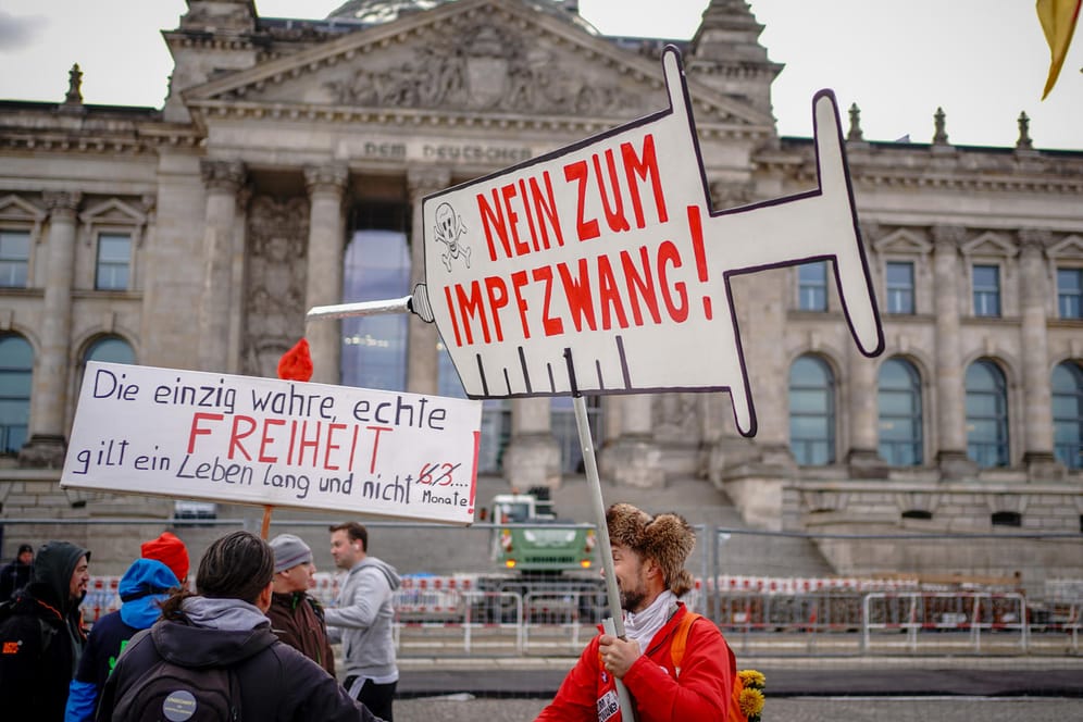 Demonstranten protestieren am Donnerstagmorgen vor dem Reichstagsgebäude mit Plakaten gegen eine Impfpflicht.