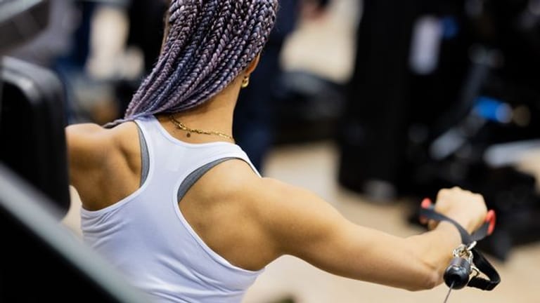 Dior führt an einem Messestand auf der Fitnessmesse Fibo ein Muskeltraining aus.