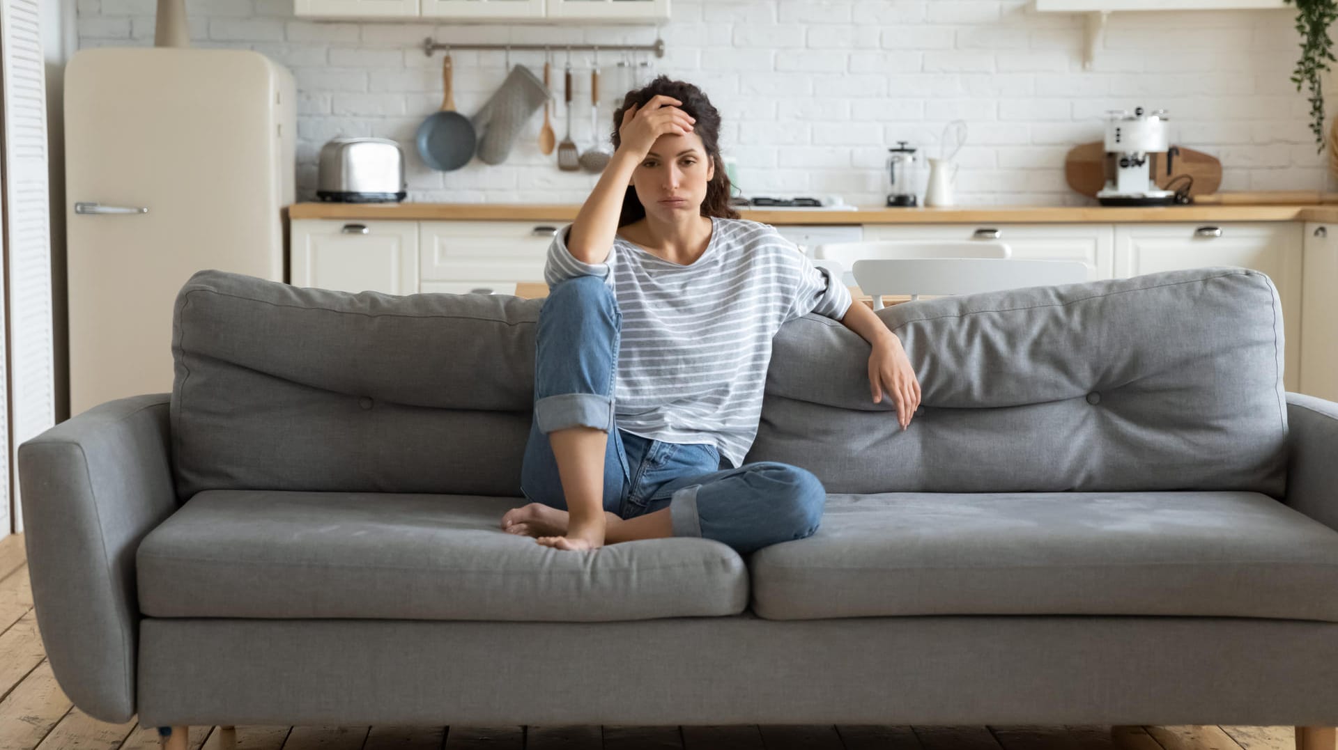 Erschöpfte Frau auf Sofa.