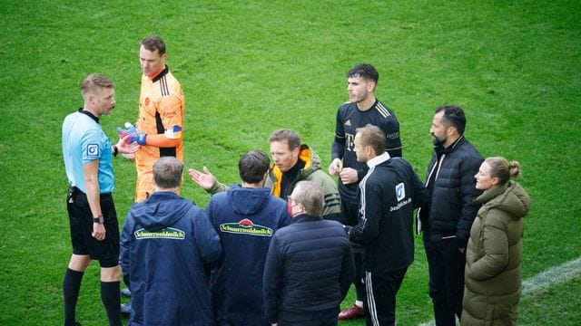 Schiedsrichter Christian Dingert (l) bespricht nach dem Wechselfehler mit Akteuren vom FC Bayern und SC Freiburg das weitere Vorgehen.