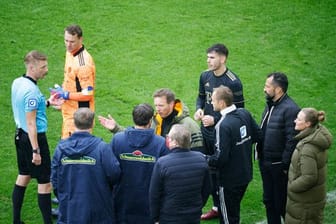 Schiedsrichter Christian Dingert (l) bespricht nach dem Wechselfehler mit Akteuren vom FC Bayern und SC Freiburg das weitere Vorgehen.