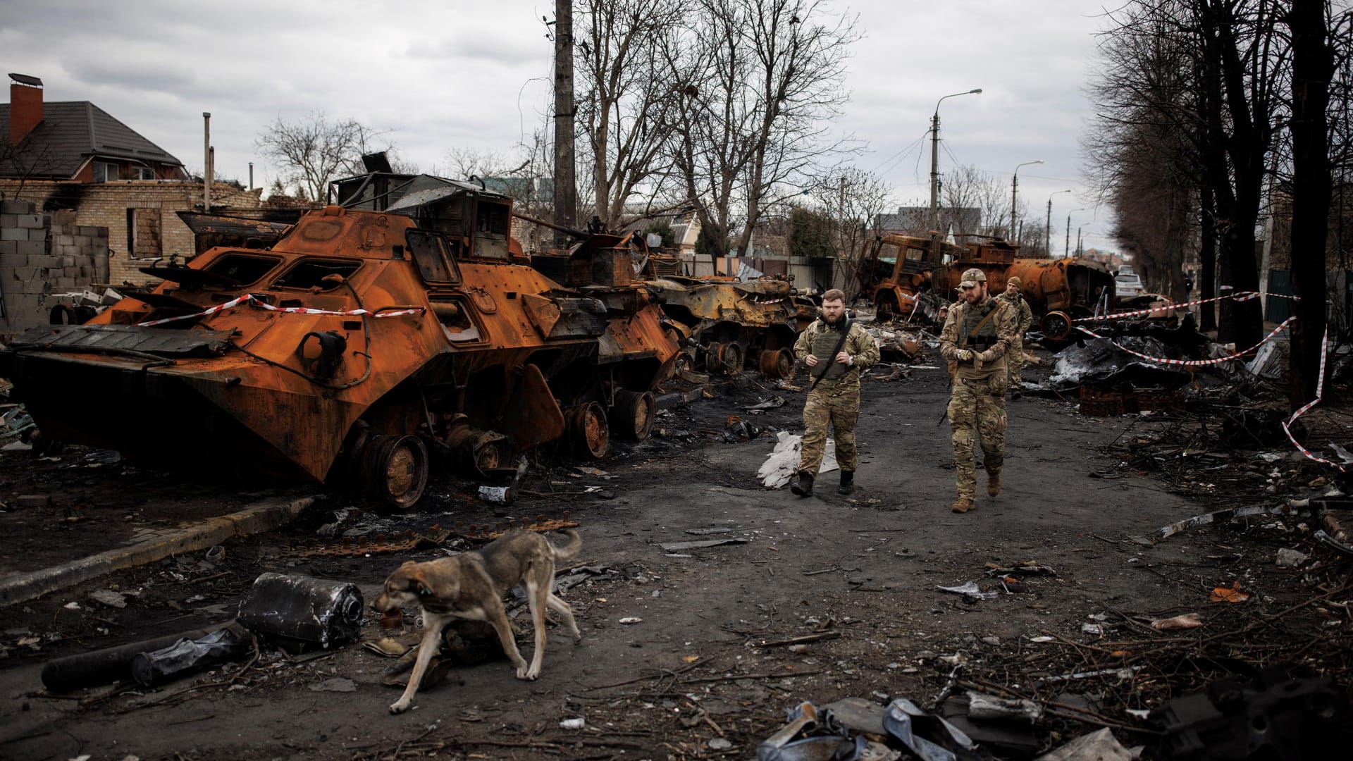 Ukrainische Soldaten laufen durch eine Blech- und Stahlwüste in Butscha.