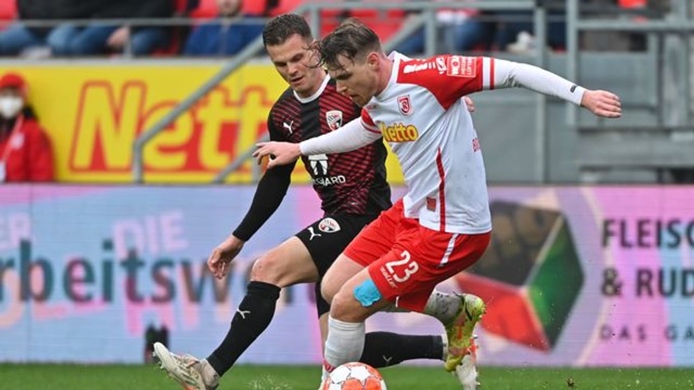 Regensburgs Steve Breitkreuz (r) versucht den Ball im Zweikampf vor Ingolstadts Florian Pick abzuschirmen.