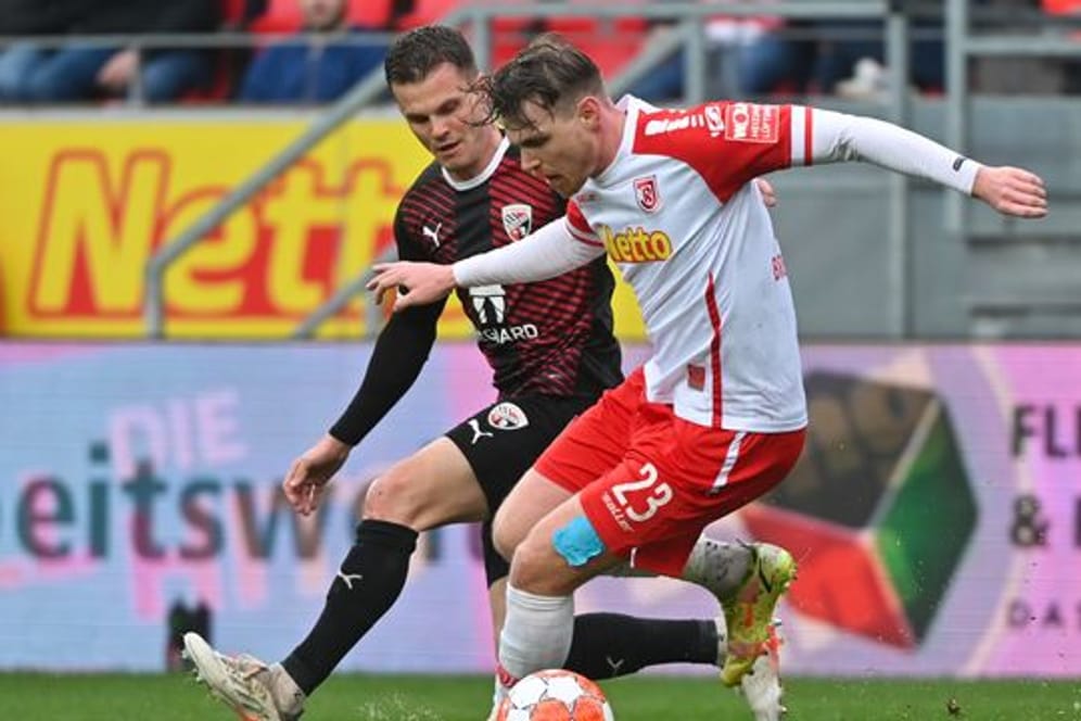 Regensburgs Steve Breitkreuz (r) versucht den Ball im Zweikampf vor Ingolstadts Florian Pick abzuschirmen.