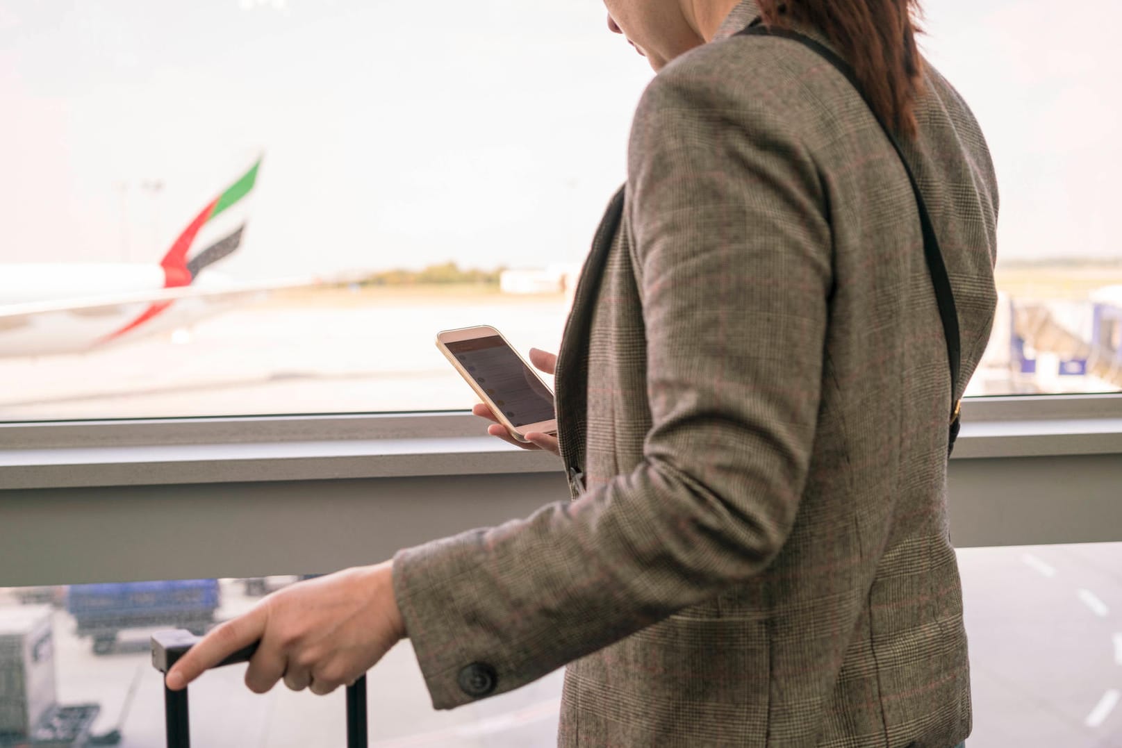 Woman at airport using smartphone with airplane in the background Budapest, Hungary ,model released, Symbolfoto PUBLICAT