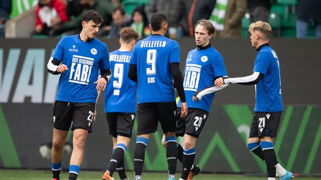 Spieler von Bielefeld tragen beim Aufwärmen ein Trikot mit der Rückennummer 9 und der Aufschrift "Gute Besserung Fabi".