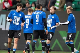 Spieler von Bielefeld tragen beim Aufwärmen ein Trikot mit der Rückennummer 9 und der Aufschrift "Gute Besserung Fabi".