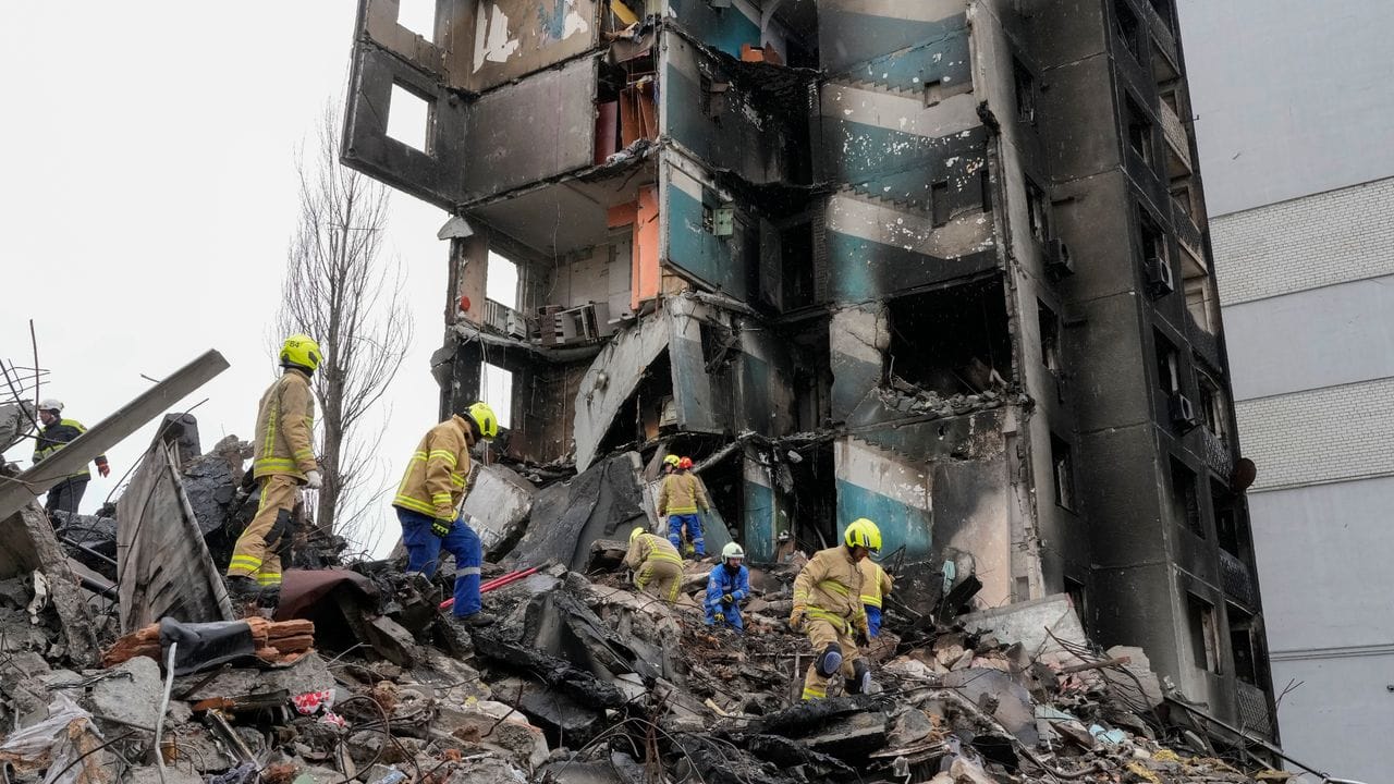 Rettungskräfte stehen in Borodjanka auf den Trümmern eines mehrstöckigen Gebäudes, das durch Beschuss des russischen Militärs zerstört wurde.