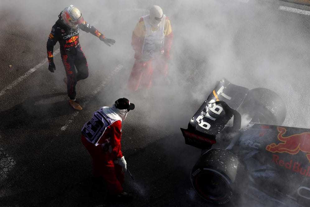 Max Verstappen (li.) vor seinem defekten Auto: Streckenposten löschen die Flammen am Red Bull.
