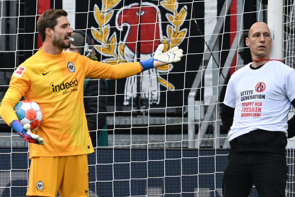 Frankfurts Torwart Kevin Trapp (l.) gestikuliert neben einem Fan der Ultras, der sich zu Spielbeginn an den Pfosten gebunden hat: Die Protestaktion zweier Fans fand bereits in der zweiten Spielminute statt.