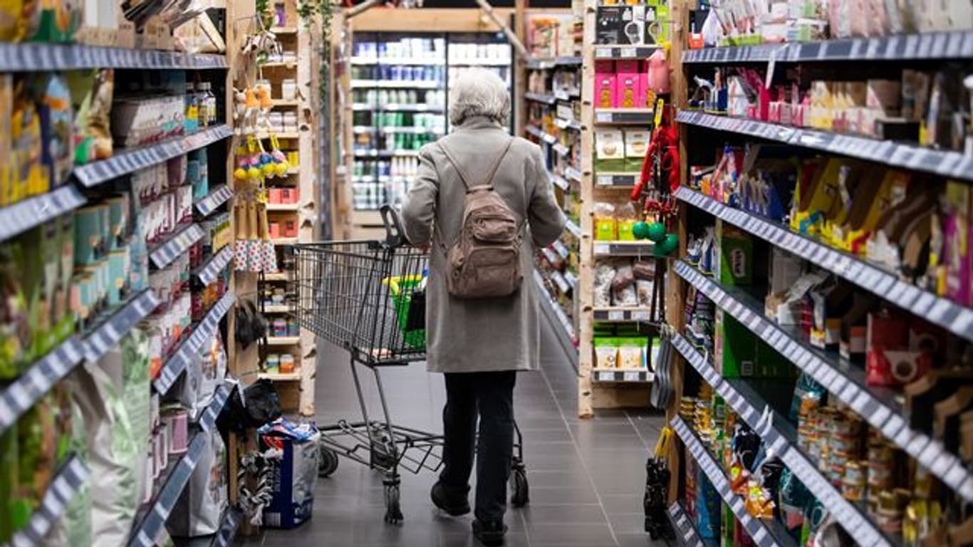 Eine Frau geht mit ihrem Einkaufswagen durch einen Supermarkt