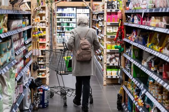 Eine Frau geht mit ihrem Einkaufswagen durch einen Supermarkt