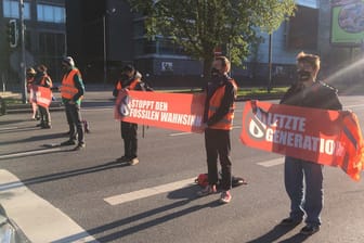 Aktivisten blockieren die Theodor-Heuss-Allee: Sie fordern den Stopp von Investitionen in fossile Brennstoffe.