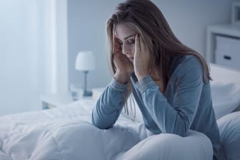 Gestresste Frau auf dem Bett: Ausreichend Schlaf ist die beste Medizin gegen Stress. Körper und Geist können zur Ruhe kommen und sich von den Belastungen des Alltags erholen.