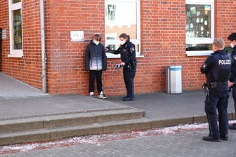Eine Polizistin mit einem der Tatverdächtigen an der Schule in Schwarzenbek.