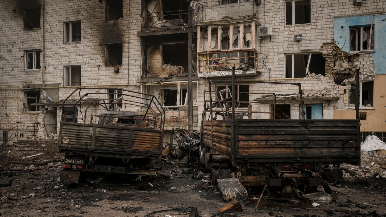 Zerstörung und Trümmer wo man auch hinschaut: Augebrannte russische Militärlastwagen vor einem schwer beschädigten Wohnhaus in einem Außenbezirk von Kiew.