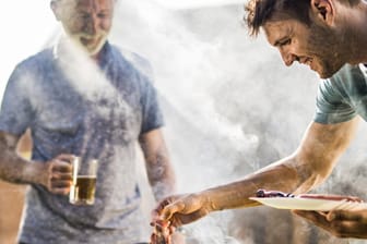 Männer am Grill (Symbolbild): Ungesunde Ernährung und Alkohol haben direkte Auswirkungen auf die Lebenserwartung.