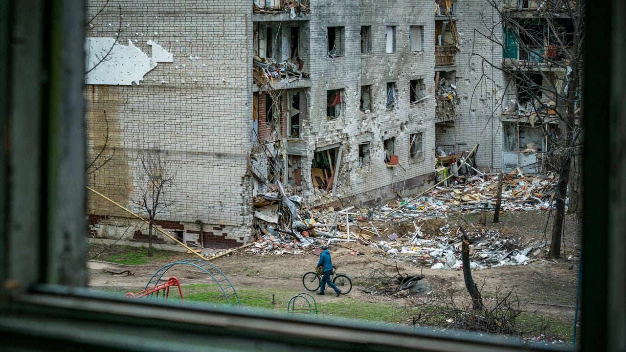 Ein Mann schiebt sein Fahrrad durch ein schwer beschädigtes Wohnviertel im ukrainischen Tschernihiw.