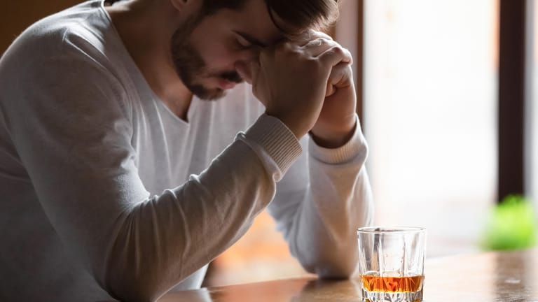 Ein Mann sitzt in der Bar vor einem Glas mit einem alkoholischen Getränk.
