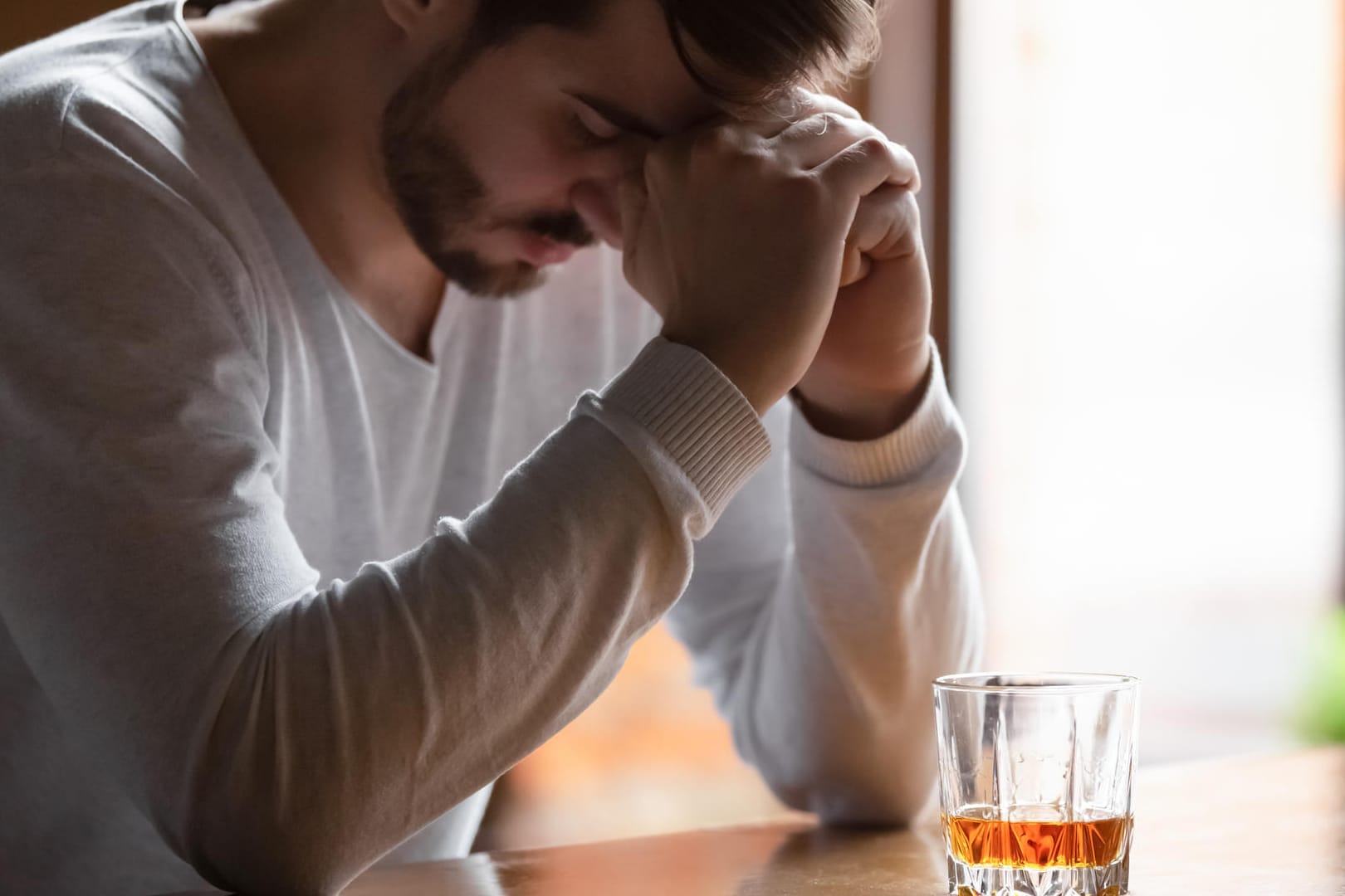 Ein Mann sitzt in der Bar vor einem Glas mit einem alkoholischen Getränk.