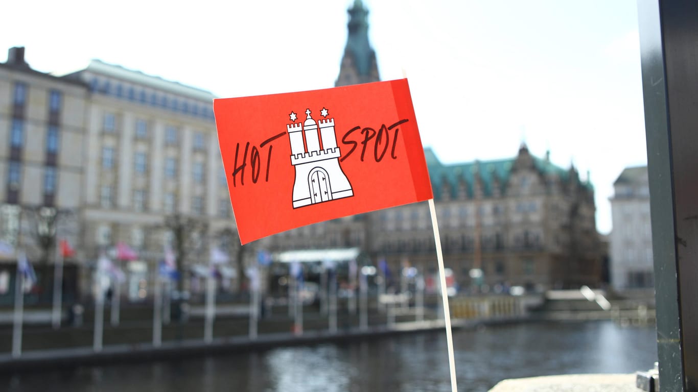 Eine Papierfahne mit dem Hamburg-Wappen und der Aufschrift Hotspot hängt an der Reesendammbrücke. Im Hintergrund das Hamburger Rathaus (Symbolbild): Die AfD ist mit ihrem Eilantrag gegen die Hamburger Corona-Hotspotregelung gescheitert.