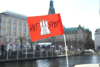 Eine Papierfahne mit dem Hamburg-Wappen und der Aufschrift Hotspot hängt an der Reesendammbrücke. Im Hintergrund das Hamburger Rathaus (Symbolbild): Die AfD ist mit ihrem Eilantrag gegen die Hamburger Corona-Hotspotregelung gescheitert.