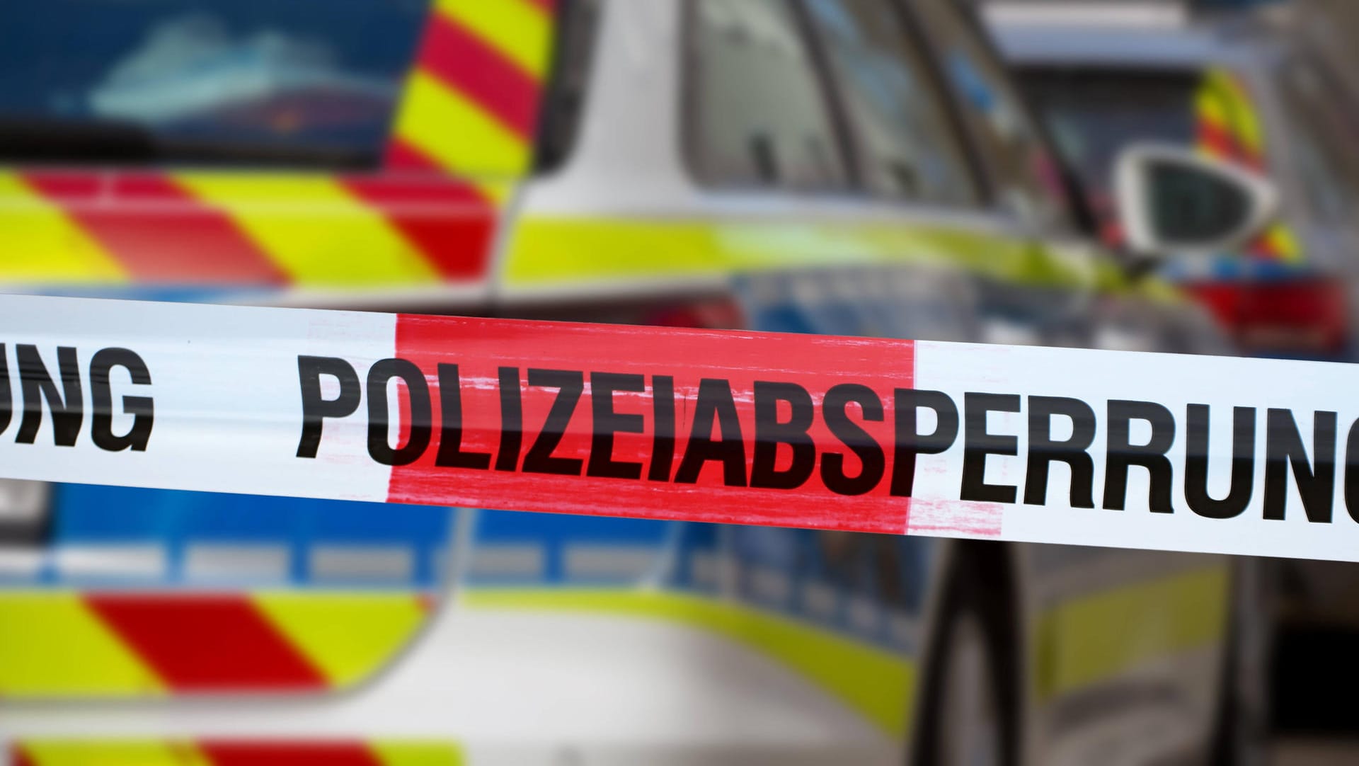 Eine Absperrung vor einem Polizeiauto (Symbolfoto): In Köln-Mülheim ist ein Mann leblos im Innenhof einen Hauses aufgefunden worden.