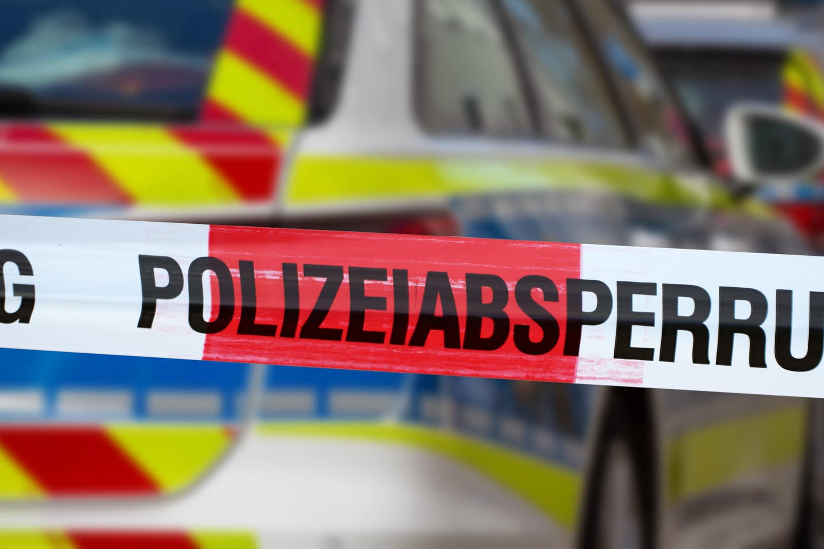 Eine Absperrung vor einem Polizeiauto (Symbolfoto): In Köln-Mülheim ist ein Mann leblos im Innenhof einen Hauses aufgefunden worden.