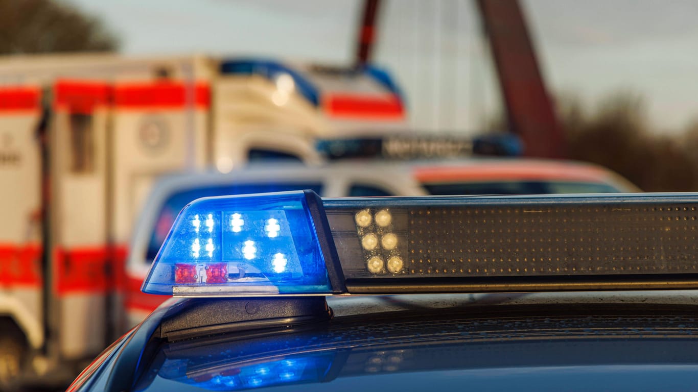 Ein Einsatzfahrzeug der Polizei setht mit Blaulicht, im Hintergrund ist ein Rettungswagen (Symbolfoto): Ein Mann ist südlich von Berlin mit einem Lkw gegen einen Brückenpfeiler gefahren und dabei tödlich verletzt worden.