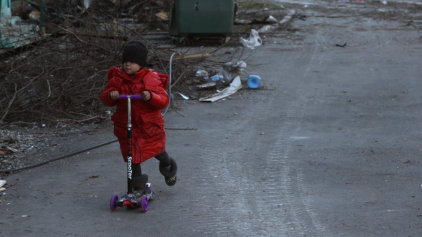 Ein Kind fährt mit einem Roller durch Mariupol: Die Stadt ist besonders schwer umkämpft, Zehntausende Bewohner warten auf eine Evakuierung.