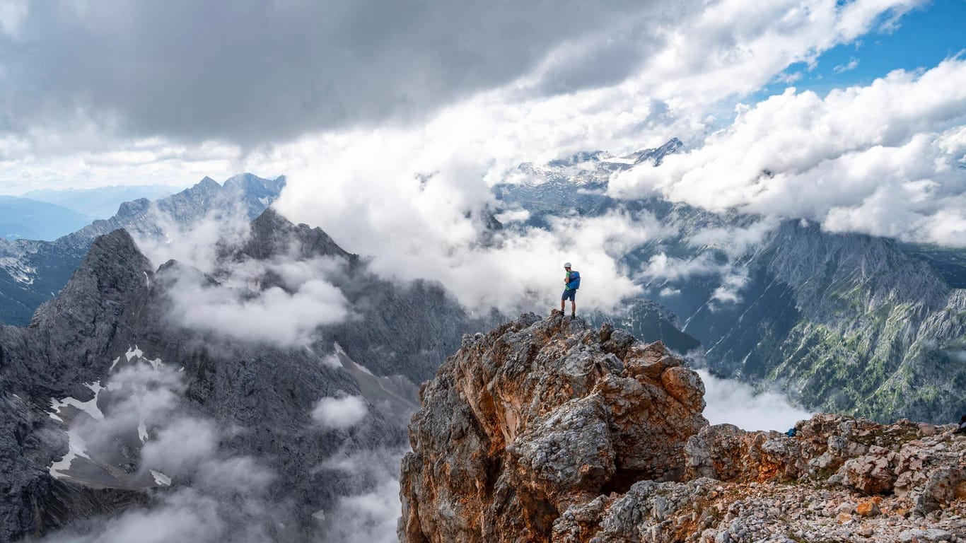 Ein Wanderer steht auf einem Felsen am Gipfel der Partenkirchner Dreitorspitze: In den Bergen sind im vergangenen Jahr 55 Menschen ums Leben gekommen.