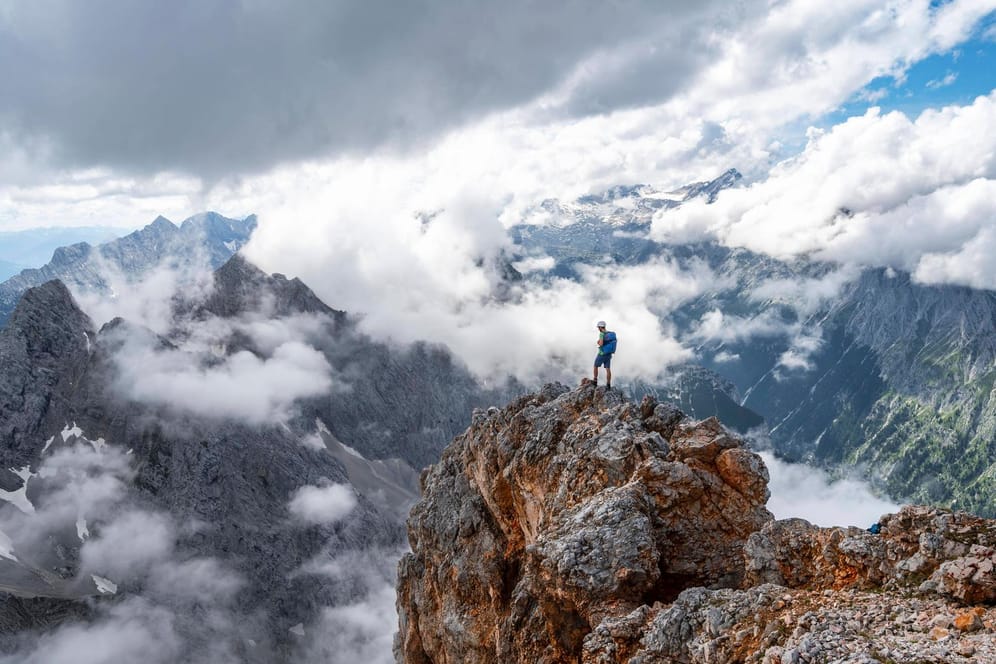 Ein Wanderer steht auf einem Felsen am Gipfel der Partenkirchner Dreitorspitze: In den Bergen sind im vergangenen Jahr 55 Menschen ums Leben gekommen.