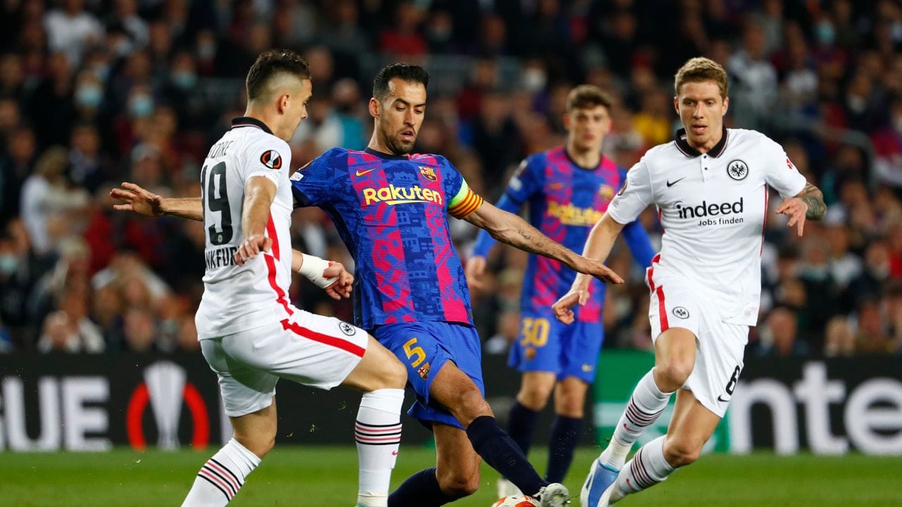 Barcelonas Sergio Busquets (M) wird von den Frankfurtern Rafael Santos Borre (l) Kristijan Jakic in die Zange genommen.